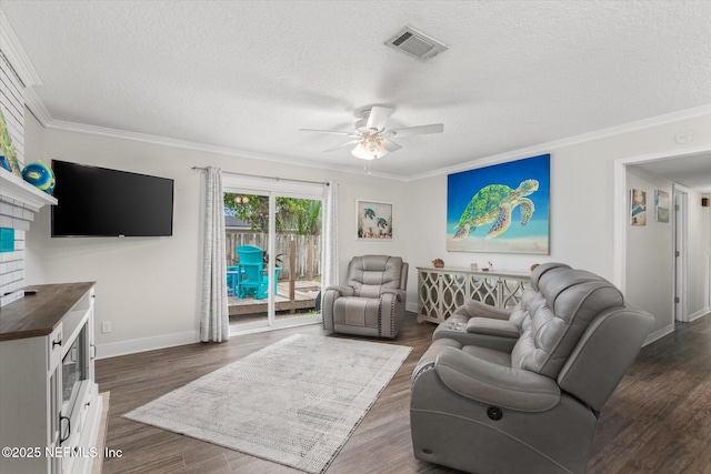 living room featuring ceiling fan, a textured ceiling, baseboards, ornamental molding, and dark wood finished floors