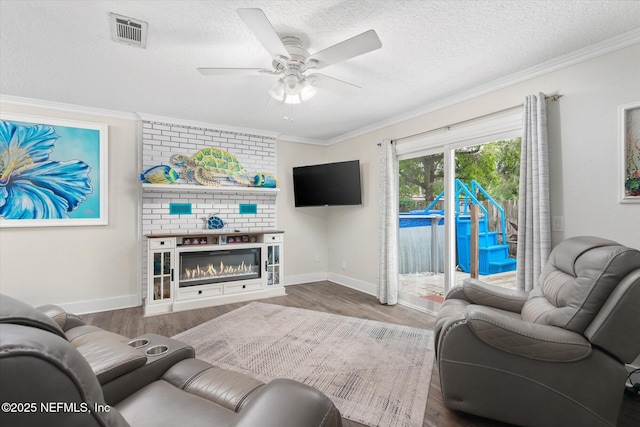 living area with crown molding, baseboards, wood finished floors, ceiling fan, and a textured ceiling