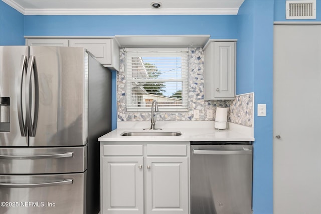 kitchen featuring appliances with stainless steel finishes, a sink, light countertops, white cabinets, and ornamental molding