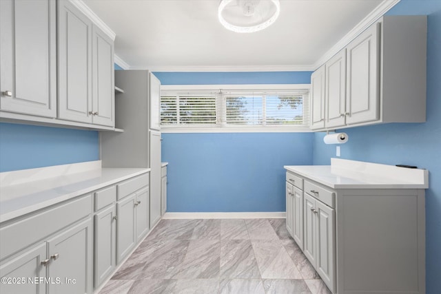 laundry room featuring light marble finish flooring, baseboards, and crown molding