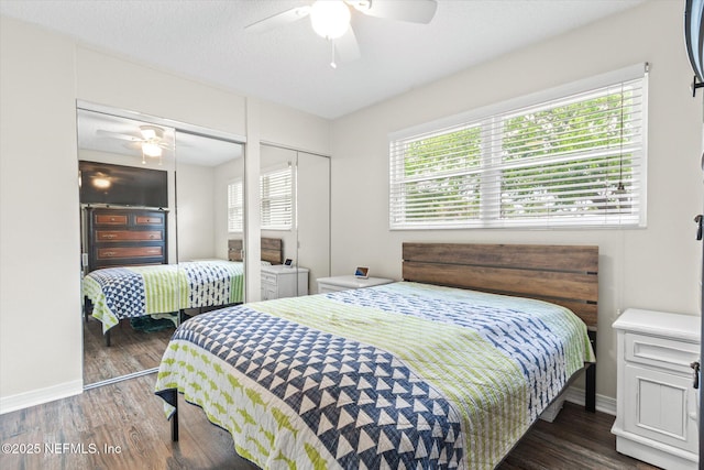 bedroom featuring two closets, wood finished floors, a ceiling fan, and baseboards