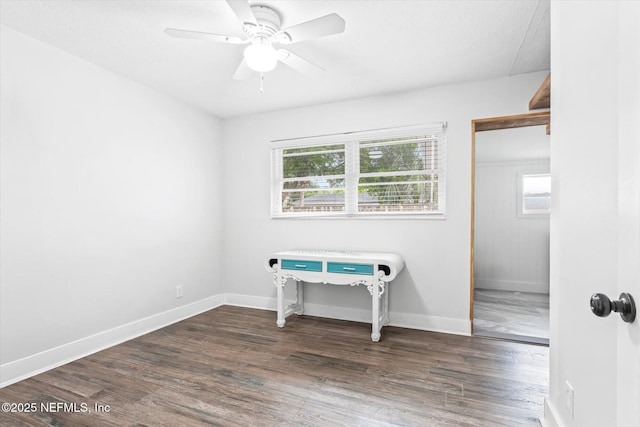 empty room featuring wood finished floors, baseboards, and a ceiling fan