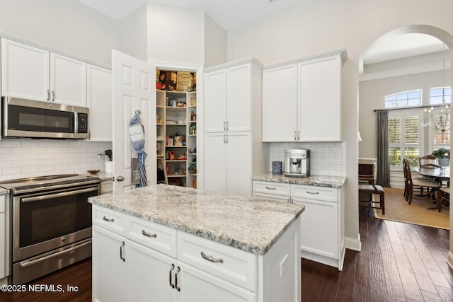 724 Piney Pl, Saint Johns, FL 32259 - kitchen featuring stainless steel appliances, arched walkways, white cabinets, dark wood-type flooring, and decorative backsplash