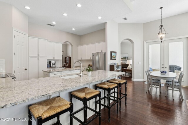 724 Piney Pl, Saint Johns, FL 32259 - kitchen featuring a sink, freestanding refrigerator, arched walkways, dark wood-style floors, and a breakfast bar