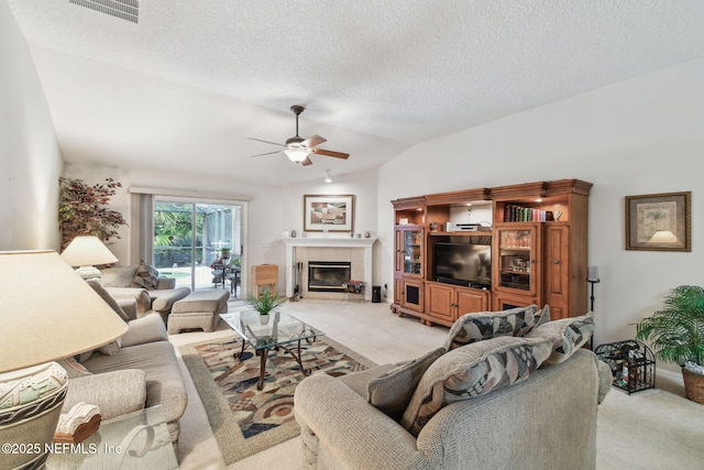 324 Hammock Grove Ct, Saint Johns, FL 32259 - carpeted living area featuring ceiling fan, vaulted ceiling, a tiled fireplace, and a textured ceiling