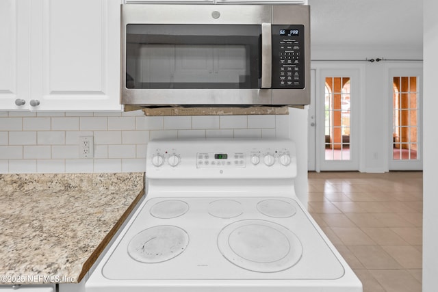 6552 La Mirada Dr E Unit 7, Jacksonville, FL 32217 - kitchen view of stainless steel microwave, electric range, tasteful backsplash, and white cabinets