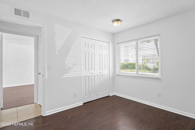 6552 La Mirada Dr E Unit 7, Jacksonville, FL 32217 - unfurnished bedroom featuring wood finished floors, a closet, baseboards, and a textured ceiling