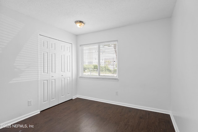 6552 La Mirada Dr E Unit 7, Jacksonville, FL 32217 - unfurnished bedroom with dark wood-style floors, baseboards, a closet, and a textured ceiling