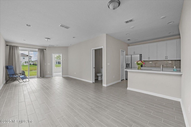698 Cherry Elm Dr, Saint Augustine, FL 32092 - unfurnished living room featuring baseboards, a textured ceiling, and light wood-style floors