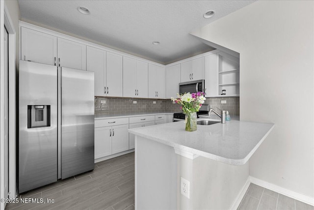 698 Cherry Elm Dr, Saint Augustine, FL 32092 - kitchen with appliances with stainless steel finishes, open shelves, white cabinetry, a peninsula, and a sink