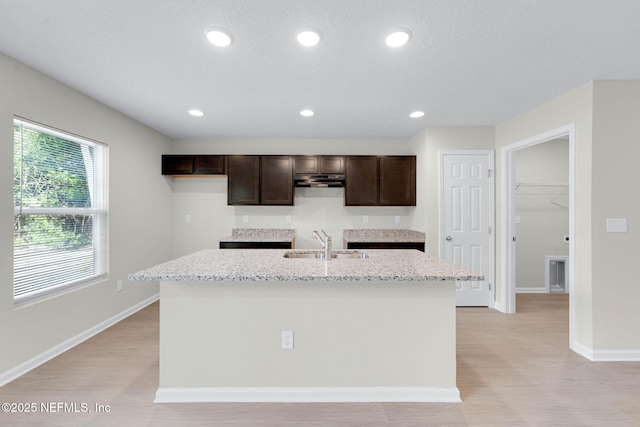 5420 Arlington Rd, Jacksonville, FL 32211 - kitchen with a sink, dark brown cabinets, a center island with sink, light wood-type flooring, and baseboards