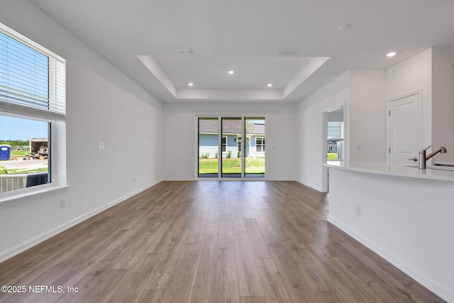 478 Cherry Elm Dr, Saint Augustine, FL 32092 - unfurnished living room with wood finished floors, a raised ceiling, recessed lighting, baseboards, and a sink