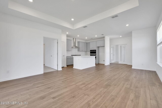 478 Cherry Elm Dr, Saint Augustine, FL 32092 - unfurnished living room with light wood-style floors, recessed lighting, a tray ceiling, and baseboards