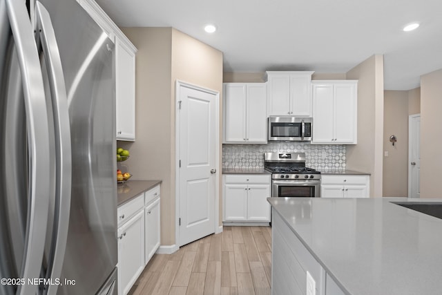 383 Saint Vincent Dr, Saint Augustine, FL 32092 - kitchen with stainless steel appliances, light wood-style floors, backsplash, white cabinets, and recessed lighting