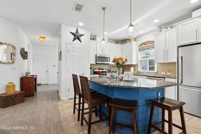 219 Heron Landing Rd, Saint Johns, FL 32259 - kitchen with appliances with stainless steel finishes, a breakfast bar, decorative backsplash, white cabinetry, and recessed lighting