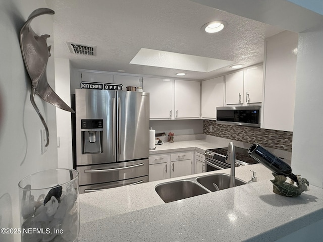 154 Del Prado Ct, Ponte Vedra Beach, FL 32082 - kitchen featuring appliances with stainless steel finishes, a textured ceiling, white cabinetry, tasteful backsplash, and recessed lighting