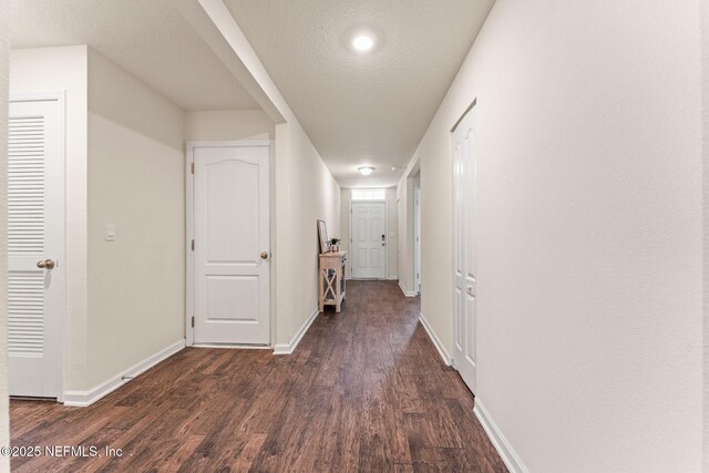 hall featuring baseboards and dark wood-type flooring