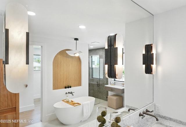 bathroom featuring healthy amount of natural light, a freestanding tub, a stall shower, and baseboards