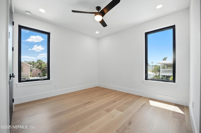 empty room featuring plenty of natural light, light wood-type flooring, ceiling fan, recessed lighting, and baseboards