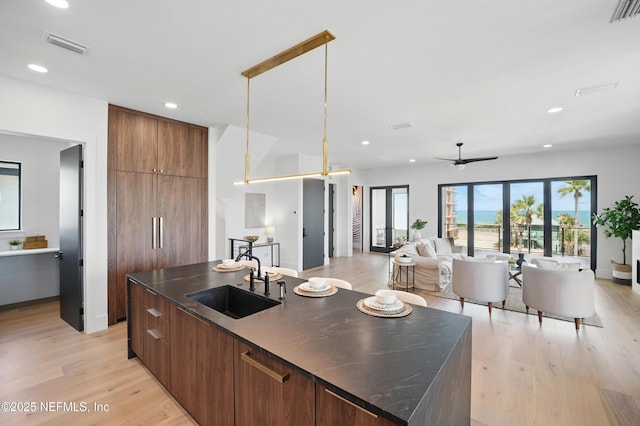 kitchen featuring modern cabinets, a sink, a ceiling fan, a kitchen island with sink, and recessed lighting
