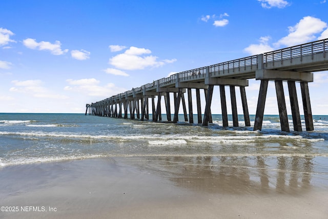 dock area with a pier and view of water and beach