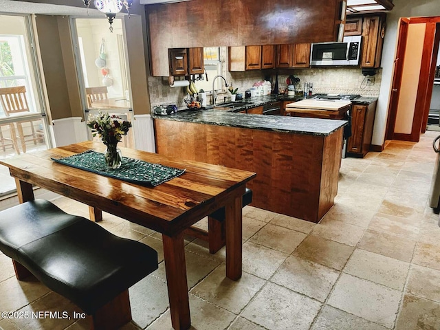 1734 Alps Ct, Fleming Island, FL 32003 - kitchen with stainless steel microwave, backsplash, stone tile floors, a peninsula, and dark stone counters