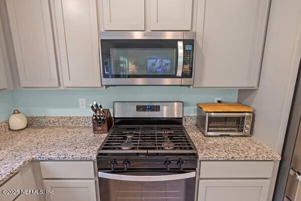 2768 Windsor Lakes Way, Green Cove Springs, FL 32043 - kitchen featuring stainless steel appliances, light stone counters, and white cabinetry