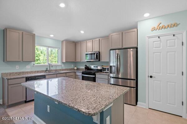 2768 Windsor Lakes Way, Green Cove Springs, FL 32043 - kitchen with appliances with stainless steel finishes, a sink, light stone counters, a kitchen island, and light tile patterned flooring