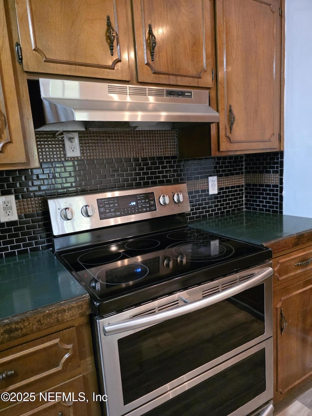 54038 Charles St, Callahan, FL 32011 - kitchen featuring range with two ovens, under cabinet range hood, tasteful backsplash, and brown cabinetry