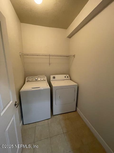 9745 Touchton Rd Unit 2522, Jacksonville, FL 32246 - washroom featuring washer and dryer, tile patterned floors, baseboards, and a textured ceiling