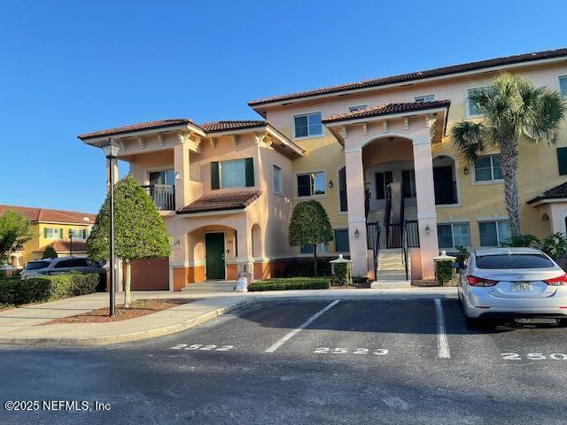 9745 Touchton Rd Unit 2522, Jacksonville, FL 32246 - view of front facade with a tile roof, uncovered parking, stucco siding, and a balcony