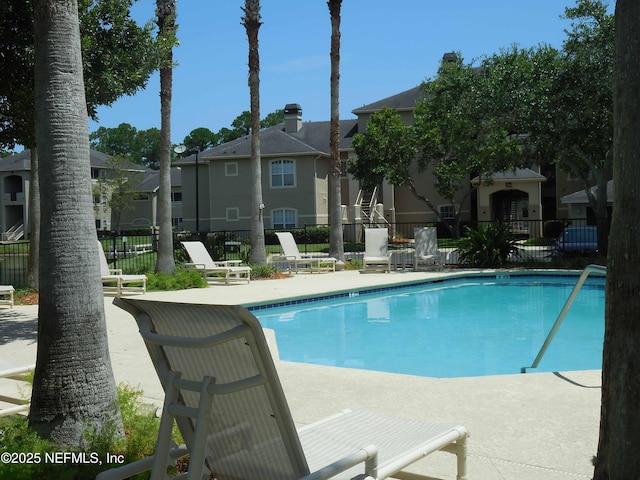 community pool featuring fence, a patio area, and a residential view