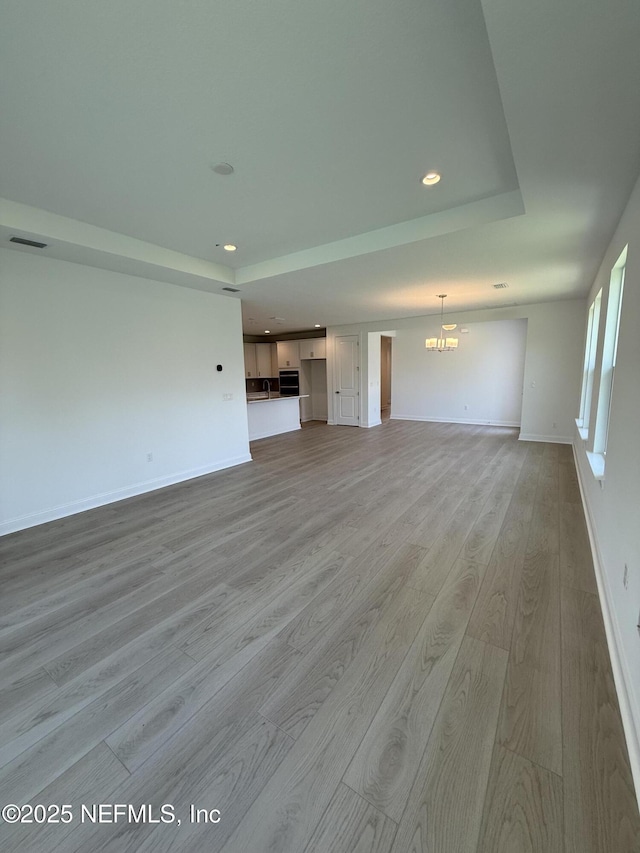 38 Mulberry Rd, Palm Coast, FL 32164 - unfurnished living room with light wood-style floors, a chandelier, recessed lighting, baseboards, and a raised ceiling