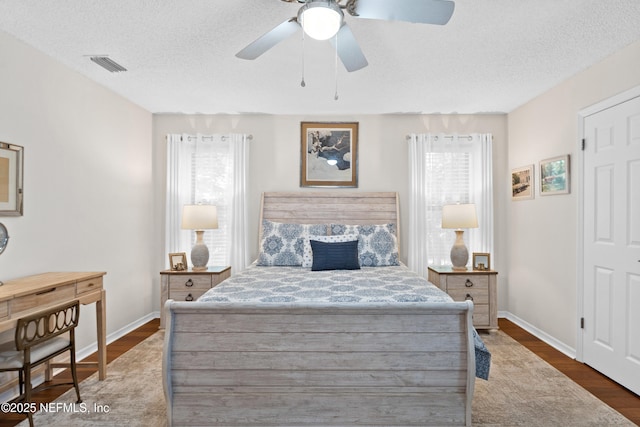 bedroom featuring dark wood-type flooring, baseboards, a textured ceiling, and ceiling fan