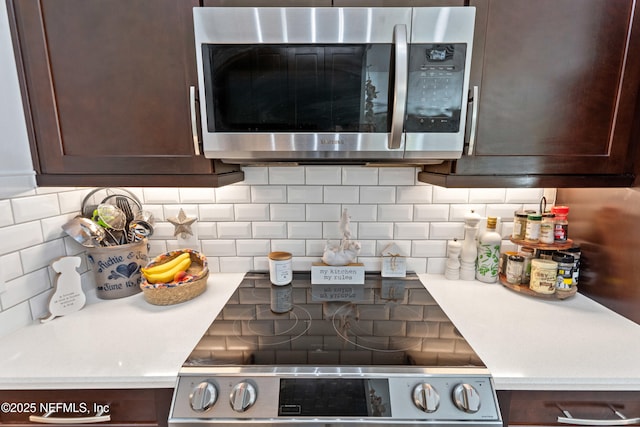 kitchen view of stainless steel microwave, dark brown cabinetry, and light countertops