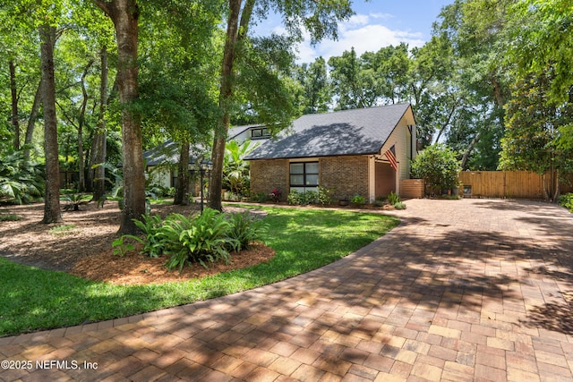 view of front facade featuring brick siding, a shingled roof, and decorative driveway