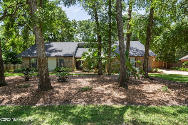 mid-century modern home with fence, brick siding, and a shingled roof