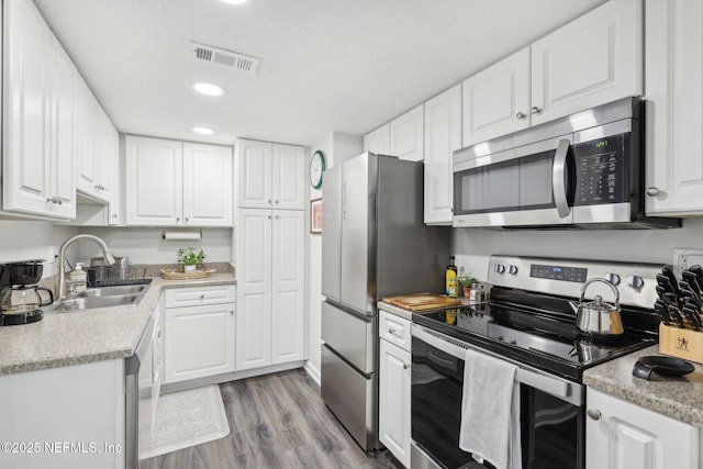303 Vista Lagoon Ct Unit C-3, Ponte Vedra Beach, FL 32082 - kitchen with appliances with stainless steel finishes, a sink, wood finished floors, white cabinetry, and light countertops
