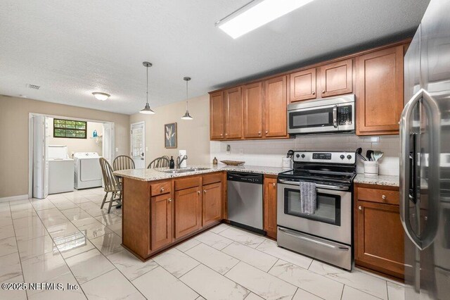 1724 Orlando Cir N, Jacksonville, FL 32207 - kitchen featuring appliances with stainless steel finishes, independent washer and dryer, light marble finish floors, brown cabinets, and a textured ceiling