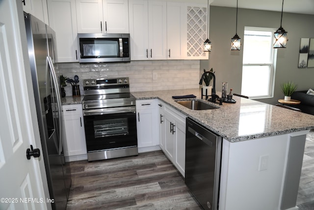1205 Neva St, Jacksonville, FL 32205 - kitchen with stainless steel appliances, a peninsula, a sink, dark wood finished floors, and white cabinetry