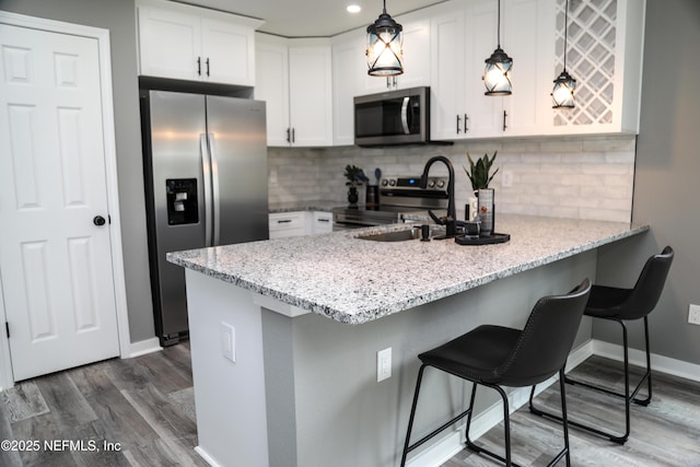 1205 Neva St, Jacksonville, FL 32205 - kitchen with appliances with stainless steel finishes, a peninsula, dark wood-style flooring, a sink, and white cabinets