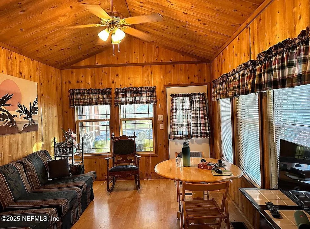 office space featuring vaulted ceiling, wood walls, wood ceiling, light wood finished floors, and a ceiling fan