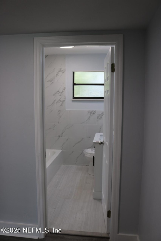2242 Lake Lucina Dr, Jacksonville, FL 32211 - bathroom featuring a tub, toilet, and tile walls