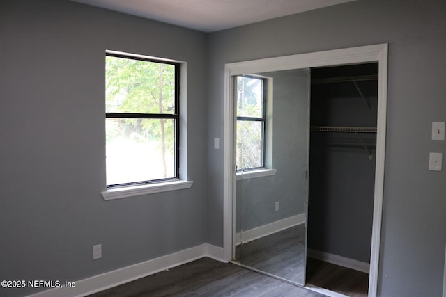 2242 Lake Lucina Dr, Jacksonville, FL 32211 - unfurnished bedroom featuring multiple windows, dark wood finished floors, a closet, and baseboards