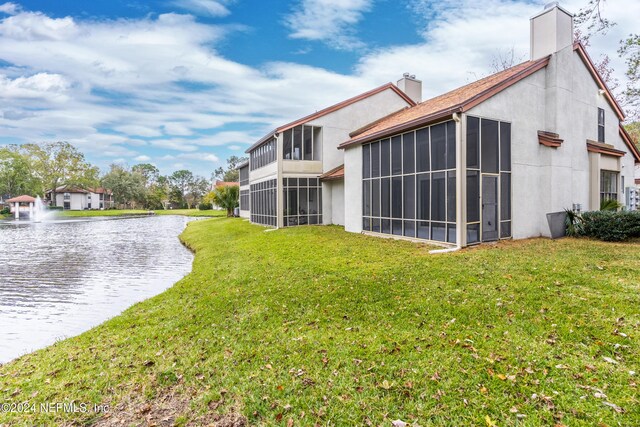 1701 Wood Hill Pl Unit 1701, Jacksonville, FL 32256 - back of house with a water view, a chimney, stucco siding, a lawn, and a sunroom