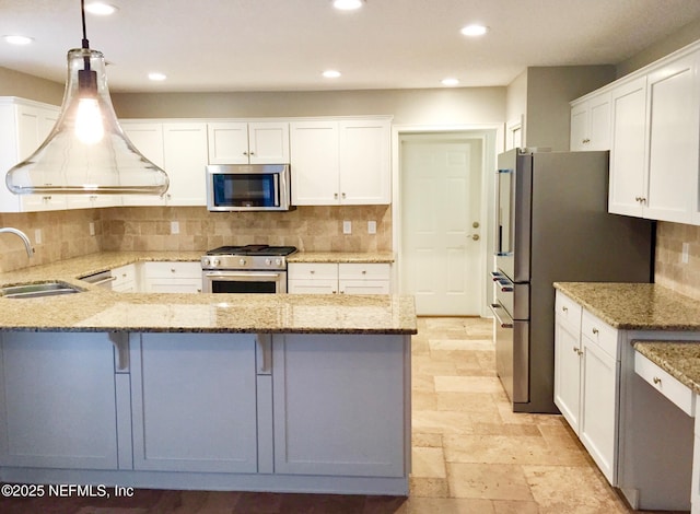 kitchen with stainless steel appliances, a sink, a peninsula, white cabinets, and recessed lighting