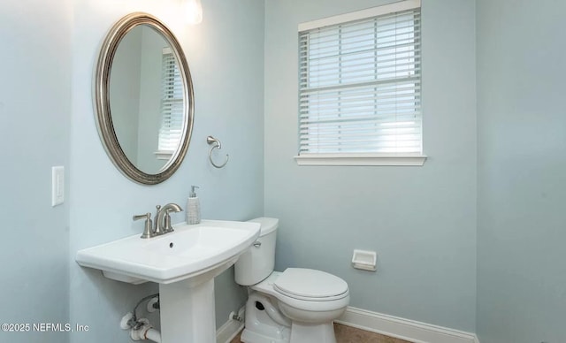 half bathroom featuring baseboards and toilet