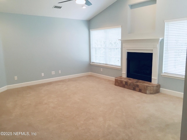 unfurnished living room featuring ceiling fan, healthy amount of natural light, light colored carpet, lofted ceiling, and a tile fireplace
