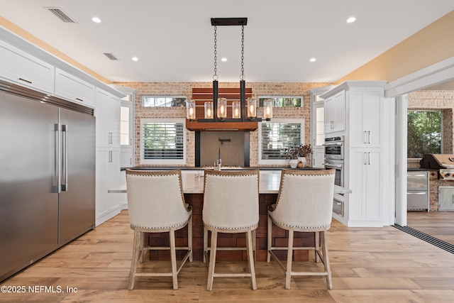 520 E Coast Dr, Atlantic Beach, FL 32233 - kitchen with stainless steel appliances, a center island, white cabinets, light wood finished floors, and recessed lighting