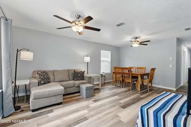 1961 Spring Drive Rd, Jacksonville, FL 32209 - living room featuring a ceiling fan, light wood-style flooring, baseboards, and a textured ceiling